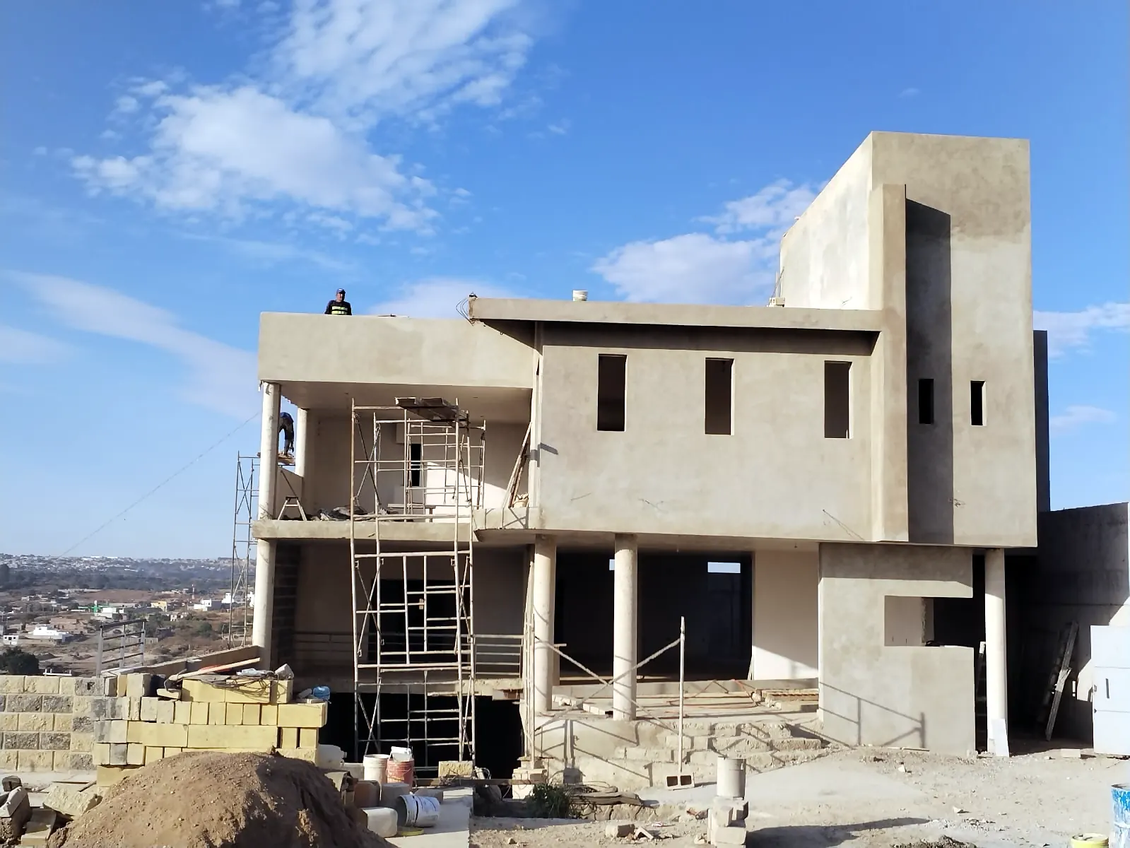 Fachada frontal de la vivienda en obra negra con andamios