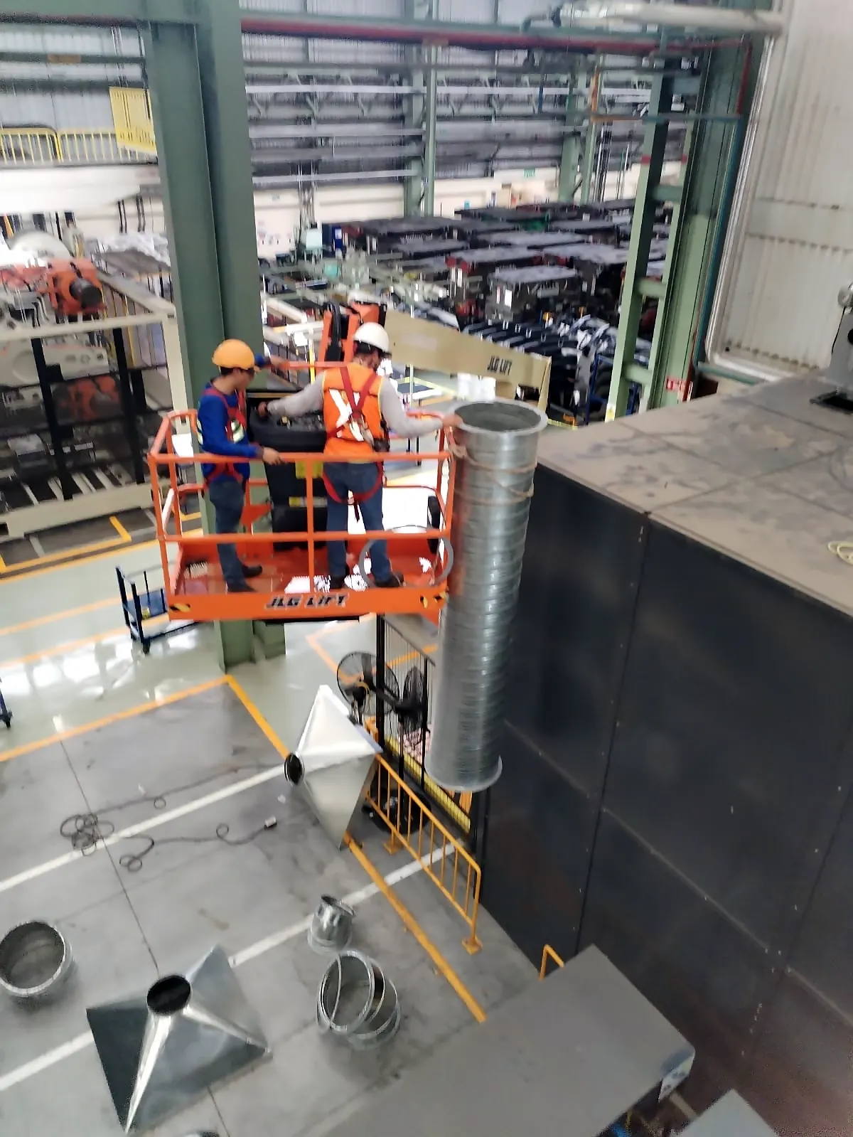Técnicos en plataforma elevadora montando un ducto